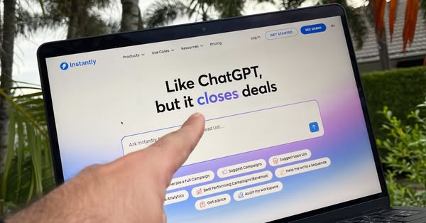 Instantly ad showing a hand pointing at a laptop screen displaying the Instantly website with the headline "Like ChatGPT, but it closes deals" and various campaign suggestion buttons.