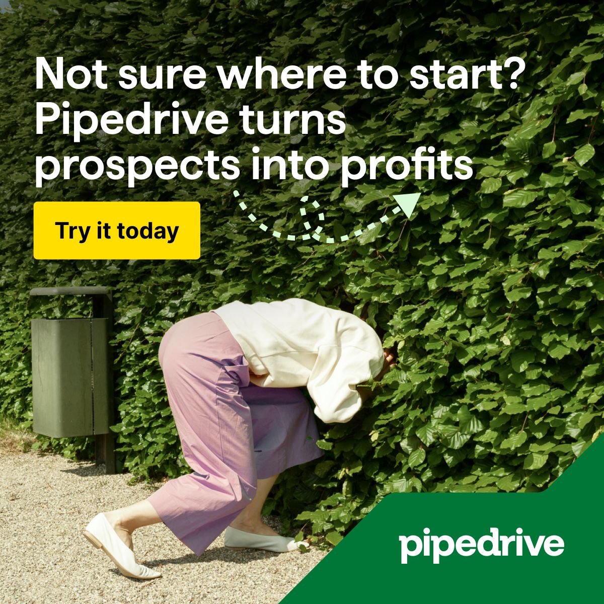 A display ad for Pipedrive featuring a person bending over and peering into a dense green hedge, as though searching for something hidden. White text overlaid reads "Not sure where to start? Pipedrive turns prospects into profits." A bright yellow "Try it today" button sits below the headline, along with a small dashed arrow graphic. The Pipedrive logo in white appears at the bottom against a green triangular corner element.